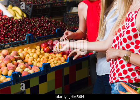 Trois jeunes femmes à l'alimentation. Les femmes choisissent des fruits. Au plan. Se concentrer sur les mains. Banque D'Images