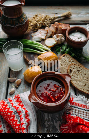 Borchtch - soupe de betteraves dans un bol d'argile sur un fond de bois, plat traditionnel de la cuisine russe et ukrainienne. Banque D'Images