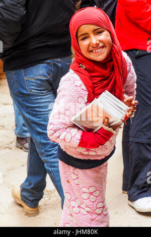 Une jeune fille bédouine portant un foulard rouge guides de vente à Pétra, en Jordanie. Banque D'Images