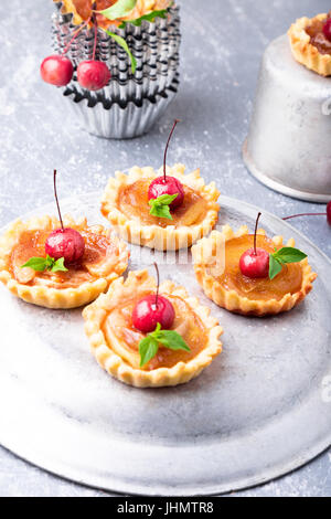 Peu de caramel Apple tartelettes sur fond gris. Tatin aux pommes paradis français Banque D'Images