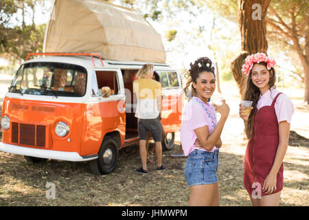 Portrait of smiling female friends having drinks en se tenant sur le terrain Banque D'Images