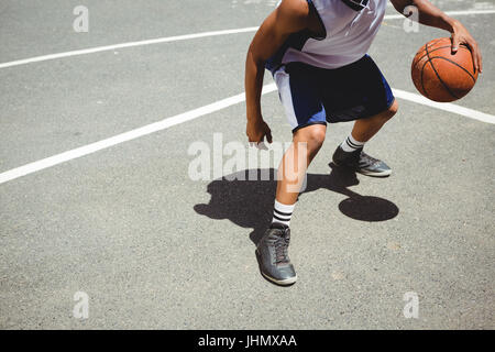 La section basse adolescent pratiquant le basket-ball à cour le jour ensoleillé Banque D'Images