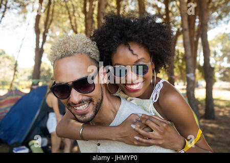 Portrait d'amis portant des lunettes de soleil tout en greffant au camping Banque D'Images