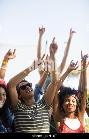 Heureux fans danse avec bras levés contre ciel lors du festival de musique Banque D'Images