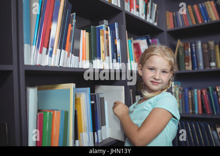 Portrait de jeune fille en choisissant à partir de la bibliothèque à étagères Banque D'Images