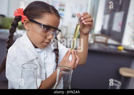 Élève d'école élémentaire concentré chimique jaune de l'examen de laboratoire scientifique. Banque D'Images