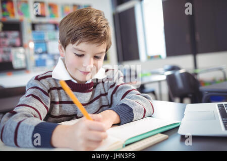 L'étude d'écolier élémentaire Smiling while sitting at desk in classroom Banque D'Images