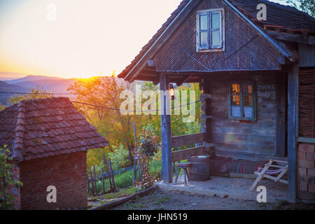 Maison en bois dans le coucher du soleil, la partie serbe de ménage anciens et traditionnels. Banque D'Images