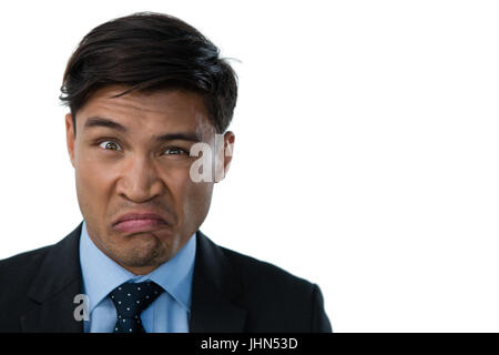 Portrait of businessman making a face contre fond blanc Banque D'Images