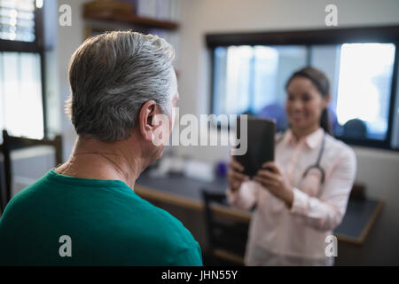 Vue arrière du senior male patient étant photographié par female therapist at Hospital ward Banque D'Images