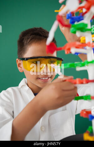 Smiling schoolboy expérimentant molécule modèle en laboratoire à l'école Banque D'Images