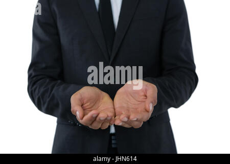 Mid section of businessman with hands cupped standing against white background Banque D'Images