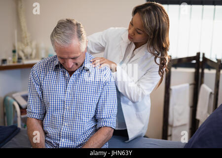 Female therapist examinant cou de male patient at Hospital ward Banque D'Images