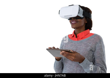 Jeune femme portant des lunettes vr lors de l'utilisation de tablet computer against white background Banque D'Images