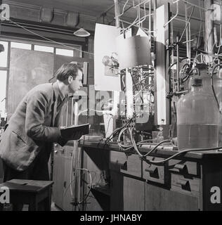 Années 1950, historiques, homme chercheur scientifique avec des études d'ordinateur portable les résultats de l'expérience et à l'aide de l'appareil de propagation de flamme dans le laboratoire de sciences à l'Université d'Oxford, Oxford, Angleterre, Royaume-Uni. Banque D'Images