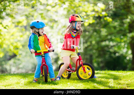 Les enfants équitation de vélo équilibre. Les enfants à vélo dans le parc ensoleillé. Petite fille et garçon ride glider vélo sur chaude journée d'été. L'apprentissage de l'équilibre d'un enfant d'âge préscolaire Banque D'Images