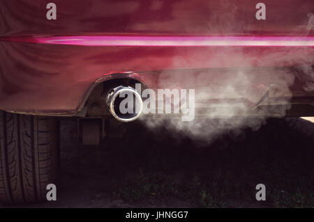 La fumée d'échappement de voiture sale vieille voiture rouge. Banque D'Images