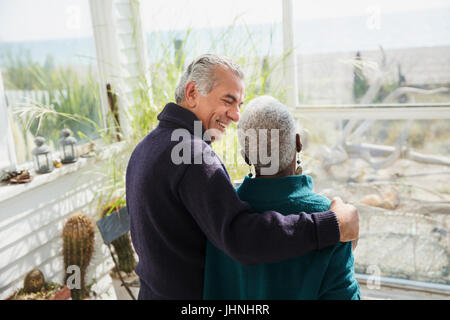 Senior couple hugging on sunny beach house sun porch Banque D'Images