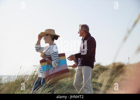 Mature couple walking on sunny beach chemin d'herbe Banque D'Images