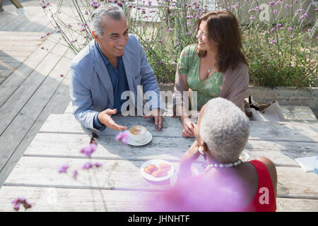 Parler d'amis d'âge mûr et de boire du café à table patio Banque D'Images