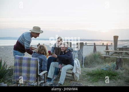Les couples d'âge mûr au barbecue, boire du vin sur sunset beach Banque D'Images