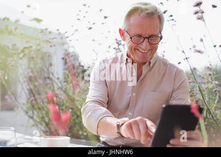 Smiling senior man using digital tablet on patio Banque D'Images