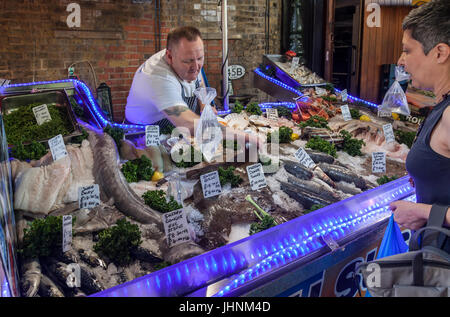 Exposant et client à un décrochage du poisson à Borough Market, le marché de l'alimentation historique à Southwark, Londres, Angleterre, RU Banque D'Images