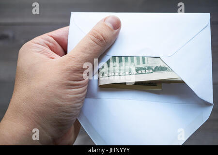 Men's main tenant une enveloppe blanche avec des dollars américains en espèces Banque D'Images