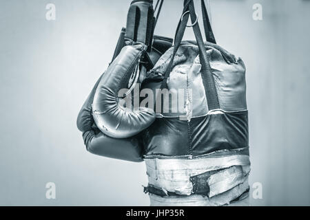 Photographie d'un vieux sac de boxe et une paire de gants de boxe Banque D'Images