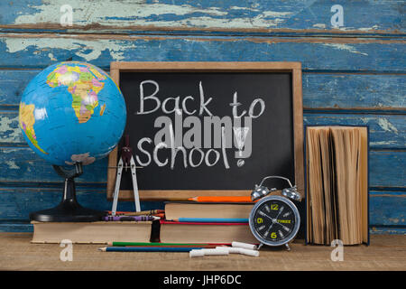 Globe, réveil, Crayons, craies, des livres et de l'ardoise avec retour à l'école texte contre blue background Banque D'Images