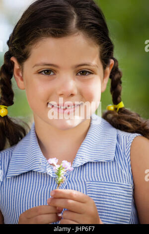 Portrait of smiling girl holding flower de tresses, au cour Banque D'Images