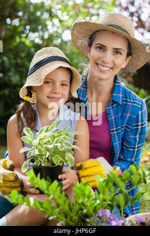 Portrait of smiling mother and daughter avec plantes en pot jardinage en arrière-cour Banque D'Images