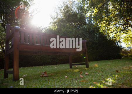 Low angle view of banc vide sur les champs contre des plantes dans la cour pendant les jours ensoleillés Banque D'Images