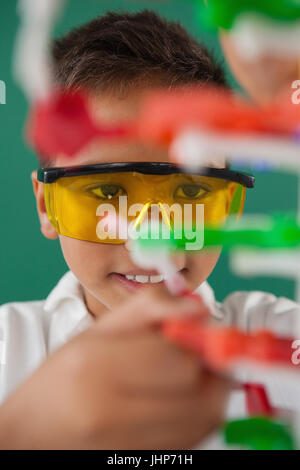 Smiling schoolboy expérimentant molécule modèle en laboratoire à l'école Banque D'Images