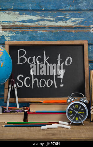 Globe, réveil, Crayons, craies, des livres et de l'ardoise avec retour à l'école texte contre blue background Banque D'Images