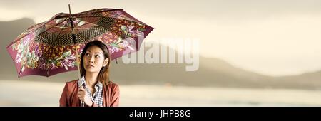 Digital composite de milliers d'femme avec parapluie jaune floue à motifs contre littoral Banque D'Images