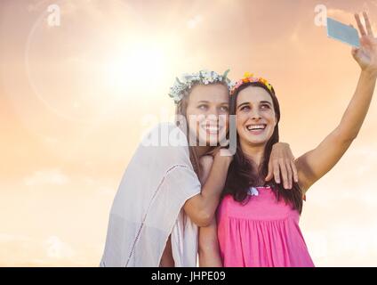 Composite numérique des femmes prenant selfies occasionnels photo devant le coucher du soleil Banque D'Images