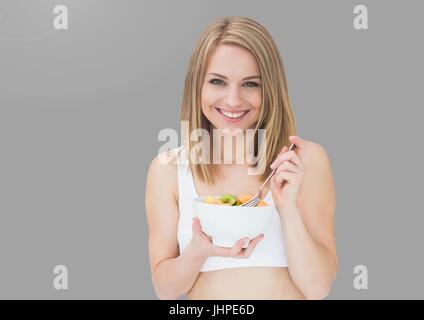 Digital composite of young woman eating salad sur fond gris Banque D'Images