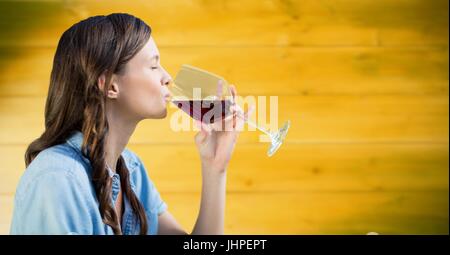 Digital composite of Woman tasting vin contre panneau jaune floue Banque D'Images