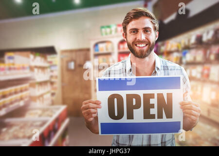 Portrait d'homme heureux propriétaire holding open sign image flou artistique contre des produits alimentaires Banque D'Images