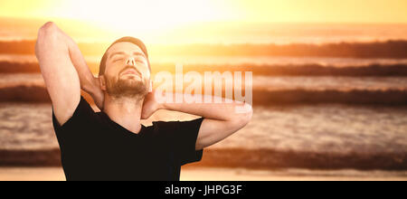 Jeune homme, les yeux fermés contre fond blanc contre l'image d'un coucher de soleil sur les vagues Banque D'Images