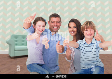 Famille heureuse gesturing Thumbs up contre un fauteuil et une table vide sur le plancher de bois franc Banque D'Images