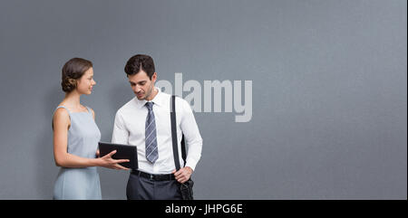 Homme d'affaires est de toucher à l'écran tandis qu'une femme est tenue le comprimé contre l'arrière-plan gris Banque D'Images