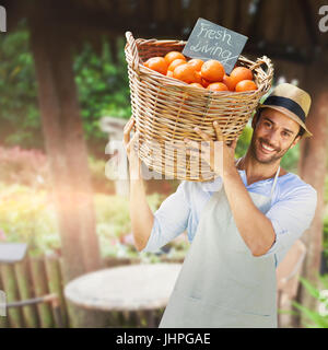 Smiling man fruits orange dans panier en osier avec des meubles de jardin contre Banque D'Images