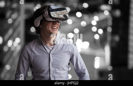 Jeune homme portant des lunettes de réalité virtuelle contre glowing road at night Banque D'Images