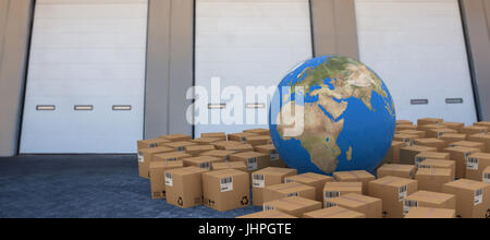 Image 3D du globe au milieu de boîtes de carton à l'encontre de porte fermée de l'entrepôt Banque D'Images