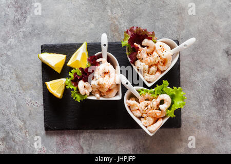 Cocktail de crevettes dans des bols en forme de cœur sur un fond gris. Sur une pierre d'ardoise noire servant de Banque D'Images