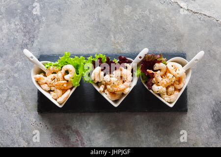 Cocktail de crevettes dans des bols en forme de cœur sur un fond gris. Sur une pierre d'ardoise noire servant de Banque D'Images