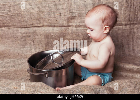 Little baby girl couvre la casserole avec un couvercle Banque D'Images