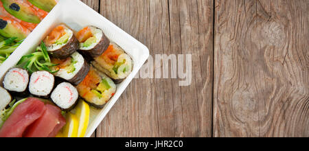 Sushi servi dans le bac sur fond blanc contre close-up de texture en bois Banque D'Images